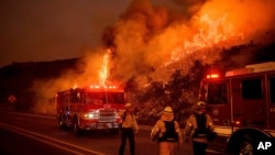 FILE - Firefighters battle the Cave Fire as it flares up along Highway 154 in the Los Padres National Forest above Santa Barbara, California, Nov. 26, 2019.