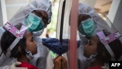 Seorang petugas medis melakukan test swab COVID-terhadap seorang anak di Surabaya (foto: AFP). RRI menutup siaran di Zona Merah termasuk RRI Surabaya. 