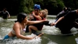 Venezuelan migrant Alvaro Calderini carries his niece across a river near Bajo Chiquito, Panama, after walking across the Darien Gap from Colombia on their way north to the United States, Nov. 9, 2024.