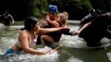 Venezuelan migrant Alvaro Calderini carries his niece across a river near Bajo Chiquito, Panama, after walking across the Darien Gap from Colombia on their way north to the United States, Nov. 9, 2024.