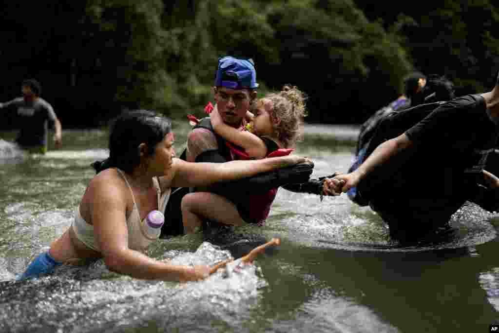 Venezuelan migrant Alvaro Calderini carries his niece across a river near Bajo Chiquito, Panama, after walking across the Darien Gap from Colombia on their way north to the United States, Nov. 9, 2024.