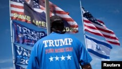 Una persona frente a unas banderas a la espera de que pase la caravana del primer ministro israelí, Benjamin Netanyahu, para reunirse con el candidato presidencial republicano Donald Trump en su resort Mar-a-Lago, en West Palm Beach. Florida, el 26 de julio de 2024.