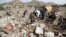 People gather around the wreckage of a house destroyed by an airstrike in the Bait Rejal village, west of Yemen's capital Sanaa, April 7, 2015.