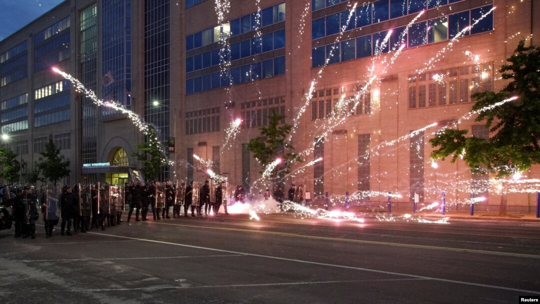 FILE - Fireworks explode near a group of law enforcement officers during a protest against the death in Minneapolis police custody of African-American George Floyd, in St Louis, Missouri, June 1, 2020.