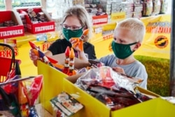 Children wear face masks as they pick out fireworks at Wild Willy's Fireworks tent in Omaha, Neb., June 29, 2020, ahead of the 4th of July holiday.