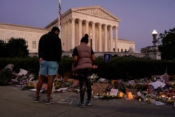 루스 베이더 긴즈버그 미 연방 대법관을 추모하는 시민들이 21일 워싱턴 대법원 앞에 꽃을 놓고 있다.
