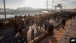 FILE - Residents of northeastern Syria walk at the Tishrin Dam to join a sit-in demanding an end to the war in the region in Aleppo's countryside, Syria, Jan. 8, 2025.