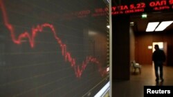 A man walks inside Athens stock exchange as a monitor shows the general index January 28, 2015. The overall Athens stock market fell almost 8 percent, while Greek five-year government bond yields hit around 13.5 percent. This marked their highest level si