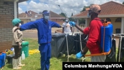 A health official sprays a colleague with a disinfectant Feb. 18, 2021, at Wilkins Hospital in Harare, where Zimbabwe launched its COVID-19 vaccination program. (Columbus Mavhunga/VOA)