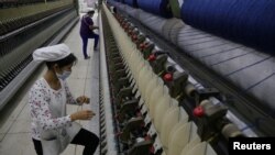 FILE - A worker disentangles wool yarn at a spinning machine at a factory owned by Hong Kong's Novetex Textiles Limited in Zhuhai City, Guangdong province, China, Dec. 13, 2016. Novetex is set to open a factory in Hong Kong that will use new technology to separate fabric blends in waste garments and produce yarn. 