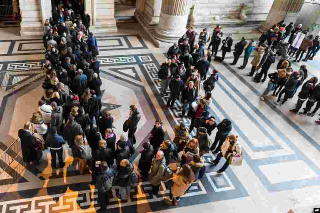 People queue as police establish a checkpoint for anyone entering the Palace of Justice in Brussels, Belgium, Jan. 16, 2015.