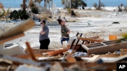 Christina Amanda, right, and Connie Huff, look for their possessions at the site of their destroyed home in the aftermath of Hurricane Michael in Mexico Beach, Fla., Oct. 17, 2018.