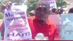 Protester holds sign that says « Ambassador M. Sison supporting the corrupt government of Haiti is racist ». (VOA/S. Lemaire)