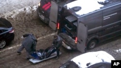 Workers load a body of Lt. Gen. Igor Kirillov, head of Russia's nuclear, biological, and chemical defense forces, into a bus after he and his assistant were killed by an explosive device planted close to a residential apartment in Moscow, Russia, Dec. 17, 2024. 