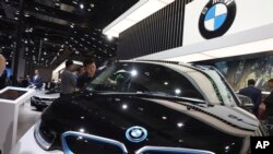 Seorang pekerja tengah membersihkan kendaraan listrik di stand BMW dalam pameran otomotif "Auto Shanghai 2019" di Shanghai, 17 April 2019. (AP Photo/Ng Han Guan, file)