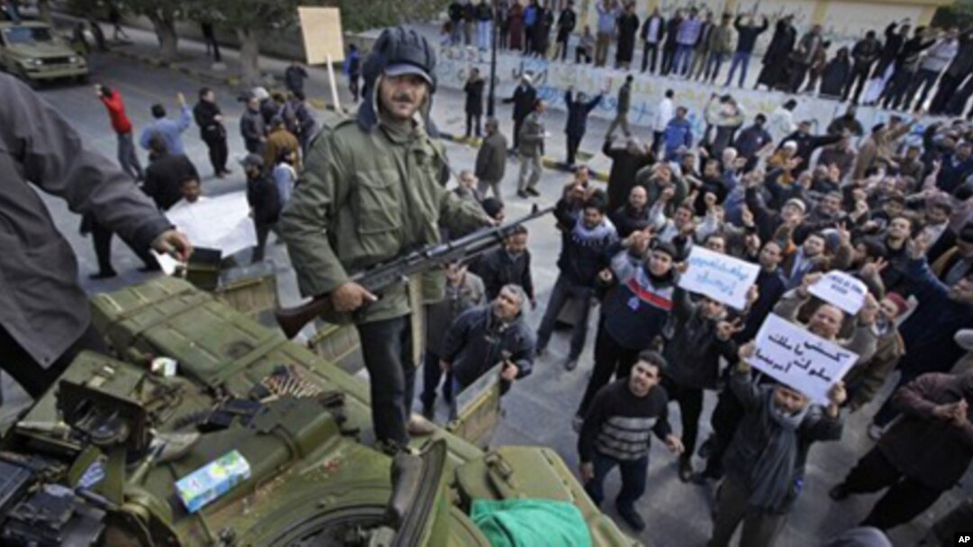 An armed man stands on top of a captured tank in Zawiya, 30 miles (50 kilometers) west of Tripoli, in Libya Sunday, Feb. 27, 2011.