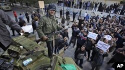 An armed man stands on top of a captured tank in Zawiya, 30 miles (50 kilometers) west of Tripoli, in Libya Sunday, Feb. 27, 2011.