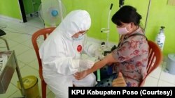 Petugas medis mengenakan APD mengambil sampel darah untuk pemeriksaan tes cepat salah satu anggota Panitia Pemungutan Suara di Puskesmas Kecamatan Lage, Kabupaten Poso, Sulawesi Tengah, 25 Juni 2020. (Foto: KPU Kabupaten Poso)