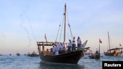 Men ride traditional wooden boats during the Katara Traditional Dhow Festival at Doha beach, Qatar, Nov. 17, 2015. 
