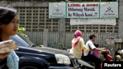 Pengendara motor melintas di depan spanduk bertuliskan penolakan terhadap kaum LGBT di kawasan Cigondewah Kaler, Bandung, Jawa Barat, 27 Januari 2016. (Foto: Reuters)