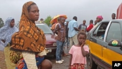 FILE- stranded people stand at a roadblock that separates Guinea and Sierra Leone.