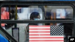 A bus passenger watches as people line up for a mobile food pantry at Barclays Center, April 24, 2020, in the Brooklyn borough of New York.