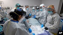 Dr. Joseph Varon, top with JV on shield, leads a team as they tried without success to save the life of a patient inside the Coronavirus Unit at United Memorial Medical Center, July 6, 2020, in Houston. 