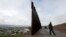 FILE - A Border Patrol agent walks near where the border wall ends that separates Tijuana, Mexico, left, from San Diego, right, Feb. 5, 2019.