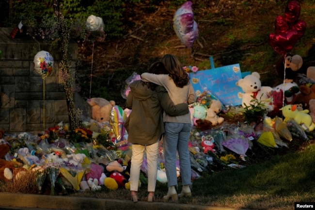 Community members embrace while visiting a memorial at the school entrance after a deadly shooting at the Covenant School in Nashville, Tennessee, U.S. March 29, 2023. REUTERS/Cheney Orr