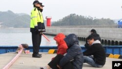 Parientes de las víctimas del ferry Sewol esperan escuchar sobre sus seres queridos en el puerto de Jindo.
