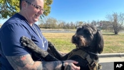 Air Force Staff Sgt. Heather O'Brien holds her service dog, Albus, on Nov. 7, 2024, in Kansas City, Kan. O'Brien is a part of Dogs 4 Valor that helps veterans and first responders with their service dogs to help manage depression, anxiety and other challenges. 