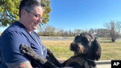 La sargento de la Fuerza Aérea Heather O'Brien sostiene a su perro de asistencia labradoodle, Albus, el jueves 7 de noviembre de 2024, en Kansas City, Kansas. 