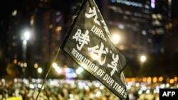 FILE - Attendees raise a flag that reads "Liberate Hong Kong Revolution Of Our Times" during a remembrance in Victoria Park in Hong Kong, June 4, 2020.