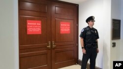 In this July 25, 2017 photo, a U.S. Capitol Police office stands guard outside a secure area in the basement of the Capitol in Washington, where the House Intelligence Committee has been conducting interviews. 