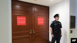 Dalam foto 25 Juli 2017, seorang polisi berjaga di lantai bawah Capitol, di depan ruangan yang digunakan Komite Intelijen DPR untuk melakukan wawancara seputar penyelidikan dugaan kolusi antara tim kampanye Presiden Donald Trump dan Rusia.