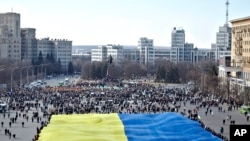 Pro-Ukrainian activists hold a huge yellow-and-blue Ukrainian flag during a rally in support of Ukraine's territorial integrity in the eastern city of Kharkiv, Ukraine, March 13, 2014.