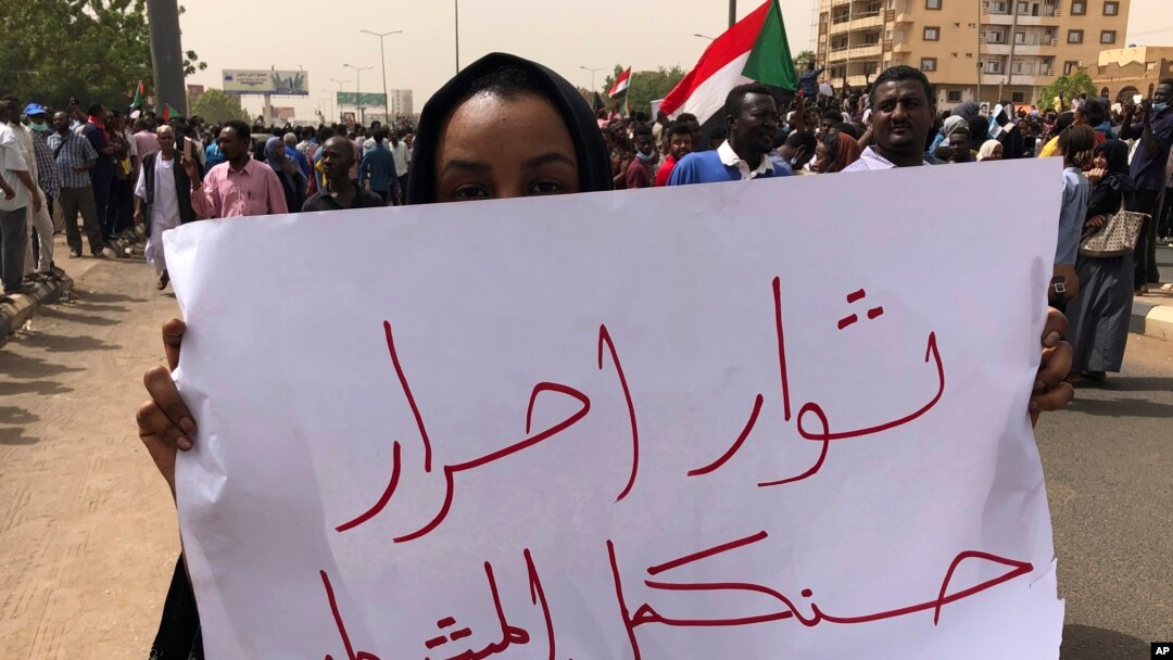 A Sudanese protester holds an Arabic placard that reads: "Free revolutionaries will continue the path," during a demonstration against the military council, in Khartoum, Sudan, June 30, 2019. 