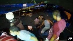 Rescuers work to help survivors and remove bodies of migrants trapped beneath the deck of a boat after it sank in the Mediterranean Sea off the coast of in Zuwara, Libya, Aug. 27, 2015.