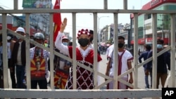 A protester wearing traditional a costume shout slogans and flashes a three-finger sign of resistance during a protest against the military coup in Yangon, Myanmar, Feb. 28, 2021. 