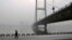 A resident walks along a street on the banks of the Songhua River near a highway bridge on a hazy day in Jilin province, Feb. 25, 2014.
