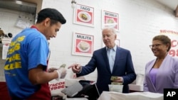 FILE - President Joe Biden, joined by Rep. Karen Bass, D, Calif., pays for a takeout order at Tacos 1986, a Mexican restaurant, in Los Angeles, Thursday, Oct. 13, 2022. (AP Photo/Carolyn Kaster)