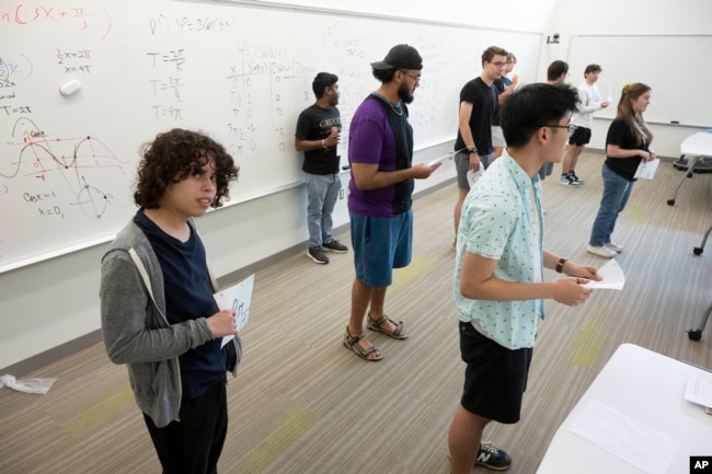 Diego Fonseca, left, and his fellow students uses their bodies to plot their location on a graph based on the number they are holding during a summer math boot camp session on Thursday, Aug. 1, 2023 at George Mason University in Fairfax. Va. (AP Photo/Kevin Wolf)