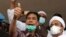 FILE - General secretary of the now-defunct Islam Defenders Front Munarman, left, who is also the lawyer of firebrand cleric Rizieq Shihab, right, gestures at reporters after Rizieq's questioning at the Regional Police Headquarters in Jakarta, Indonesia o