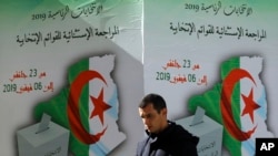 FILE—A man walks past a poster asking citizen to register to vote in Algiers, February 5, 2019.