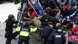 FILE - Pro-Trump protesters tear down a barricade as they clash with Capitol Police during a rally to contest the certification of the 2020 U.S. presidential election results, Jan. 6, 2021.
