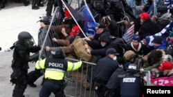 FILE - Pro-Trump protesters tear down a barricade as they clash with Capitol Police during a rally to contest the certification of the 2020 U.S. presidential election results, Jan. 6, 2021.