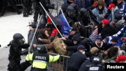 Los manifestantes pro-Trump derriban una barricada mientras chocan con la policía del Capitolio durante un mitin para impugnar la certificación de los resultados de las elecciones presidenciales de los EE. UU. 2020 por parte del Congreso de los EE. UU.