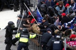 FILE - Pro-Trump protesters tear down a barricade as they clash with Capitol Police during a rally at the U.S. Capitol Building in Washington, Jan. 6, 2021.
