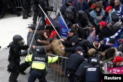 FILE - Pro-Trump protesters tear down a barricade as they clash with Capitol Police during a rally to contest the certification of the 2020 U.S. presidential election results by the U.S. Congress, at the U.S. Capitol Building in Washington, Jan. 6, 2021.