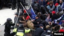 Pristalice Donalda Trumpa ruše barikadu dok se sukobljavaju sa policijom Kapitola tokom napada na zgradu Kongresa, Vašington, 6. januar, 2021. 